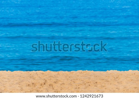 Blurred background sea. Abstract summer background. Glare of the sun against the sea, beautiful bokeh. Yellow sand on the beach and the blue sea. Minimalist seascape.