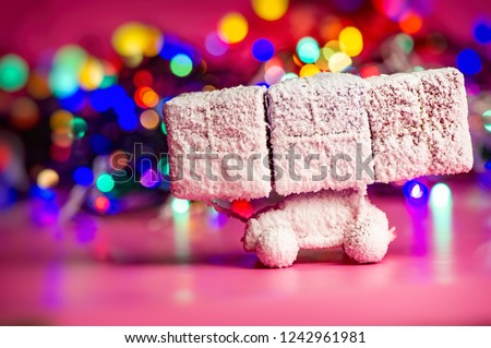 toy car covered with snow carries New Year's gifts against the backdrop of illumination. Christmas composition, winter season. Festive background.