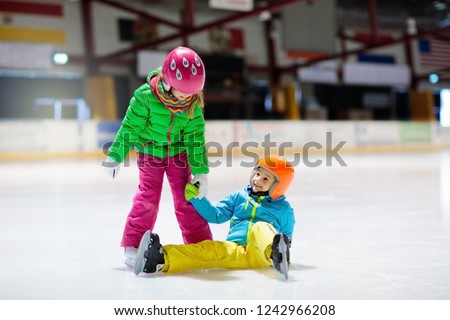 Child skating on indoor ice rink. Kids skate. Active family sport during winter vacation and cold season. Little girl and boy in colorful wear training or learning ice skating. School sport clubs