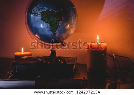 globe in candles light background on a wooden surface with stones and ancient books
