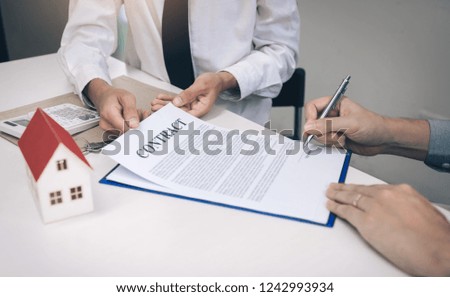 Home sales people are filing a signed contract for buying a home at desk in office room.
