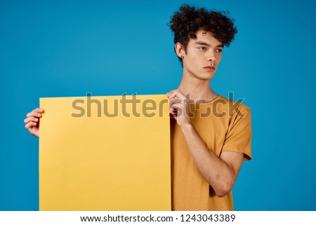 man with a yellow sheet of paper on a blue background                    