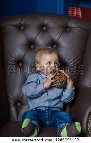 A little boy is sitting in an old leather chair.