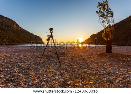 Professional camera taking picture film video of scenic orange sunrise or sunset over sea surface, Greece Peloponnese.