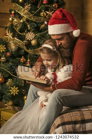 Xmas party celebration, fathers day. Christmas happy child and father read book. Winter holiday and vacation. Santa claus kid and bearded man at Christmas tree. New year small girl and man, fairytale.