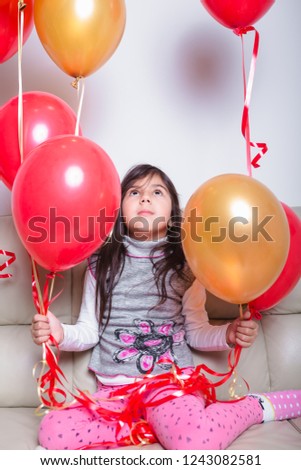 Baby Girl Holding Balloons celebrating her Birthday
