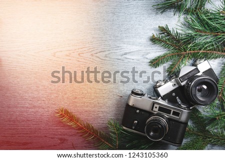 Top View of Vintage Camera Between Christmas decorations, Christmas tree, warm and cold toning, lights, garlands, bokeh on Wooden Texture