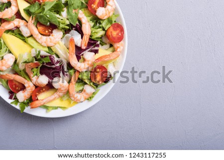 Mix of salad with shrimps , avocado and cherry tomatoes . Healthy food background