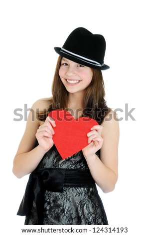 Smiling teenage girl holding valentine heart cut out from red paper over white background