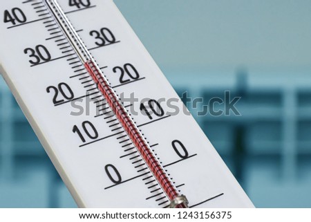 Closeup photo of household alcohol thermometer showing temperature in degrees Celsius. Against the background of a heating radiator