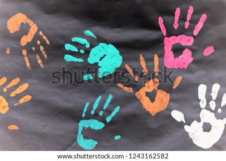 Color prints of kid's hands on a white sheet.
