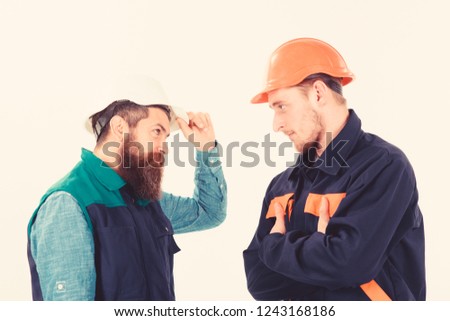Builder, architect, engineer with serious face. Conflict at site concept. Conflict, confrontation, leadership. Men in hard hats, uniform, builders, looking strictly in eyes isolated white background