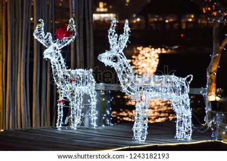 Picture of New Year decorated branches of firs, toy deer on blurred background