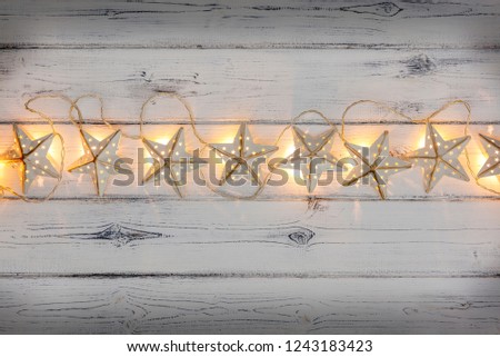 A string of golden star christmas lights, on a destressed woodern background, creating a banner with empty space for copy