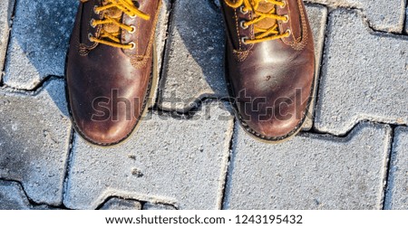 First person view of shoes. Winter walk concept. View from above on brown boots on cobblestone pavement background
