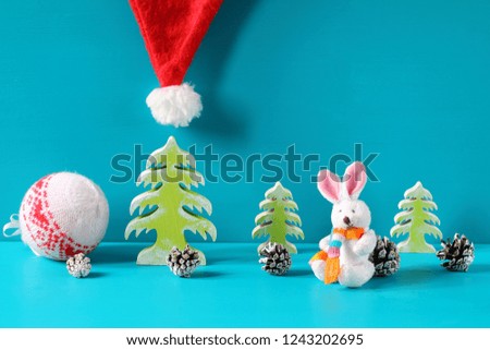 Christmas and New Year decorations with white bunny figurine are on a light blue wooden background.