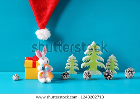 Christmas and New Year decorations with white bunny figurine are on a light blue wooden background.
