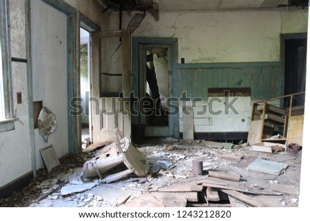 Interior of abandoned farmhouse filled with garbage and peeling walls