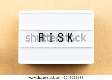Light box with word risk on wood background