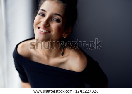 smiling woman in black dress near the window                         