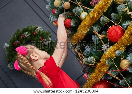 little girl dressing up a christmas tree
