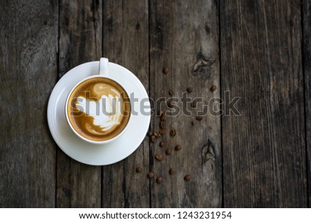The top view on a cup of coffee on a wooden table