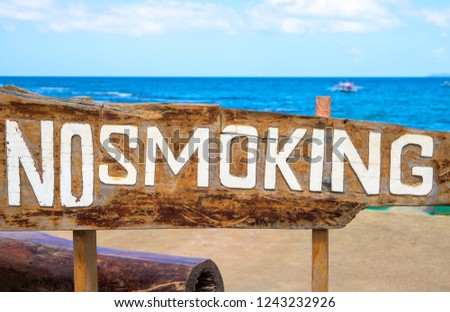 No Smoking sign on driftwood by sea. Prohibition of smoke on tropical beach. Clean seaside environment without smoking. Smoking ban sign on wood background. Seaview with wooden sign. Healthy lifestyle