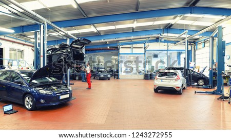 job and workplace - mechanic in a workshop repairing a car  Royalty-Free Stock Photo #1243272955