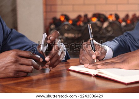 Close-up of African American businessmen in business negotiations. Only the hand in focus. Pen and notebook and phone in the hands of businessmen. Wine glasses. The concept of business negotiations.