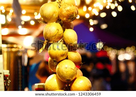 A bunch of onions hanging like a decoration in a Christmas market with warm light and fairy lights, bokeh in background in Riga, Latvia