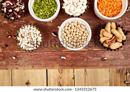 Collection set of beans and legumes red turkish lentils, chickpeas, beans, peanuts, peas, canadian lentils on wooden table. Bowls of various lentils. Rustic background. Top view. Copy space.