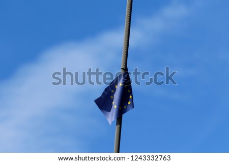 European Union flag waving in the evening at wire rope. Small flag at steel cable, at blue sky and cirrostratus in the Background.