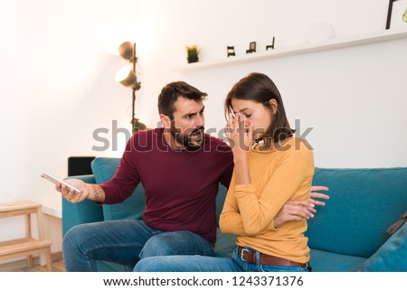 Young beautiful couple fighting at home, boyfriend shouting at girlfriend, she puts her hand on her head. Stressed out couple having problems. Divorce concept. Royalty-Free Stock Photo #1243371376