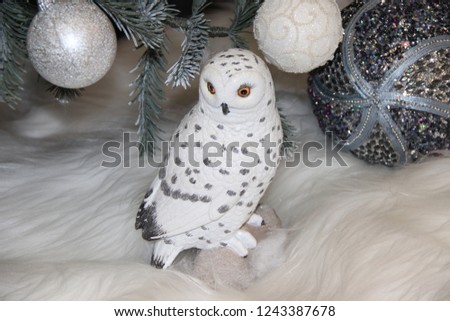 white owl sitting in the snow under a decorated Christmas tree