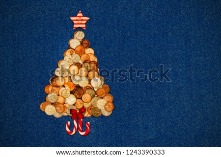 Christmas tree from American coins with red bow, star, candy cane on blue denim background, copy space, text place, top view