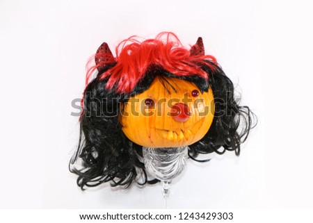 scary pumpkin decorated for the celebration of heluina in a wig with horns