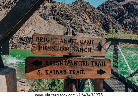 A couple of wooden trail signs on the Bright Angel Bridge by the green Colorado River in the Grand Canyon at Grand Canyon National Park in Arizona Royalty-Free Stock Photo #1243436275