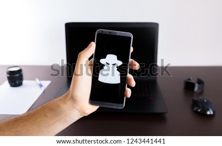 Holding a smartphone on hand with a spy sign logo