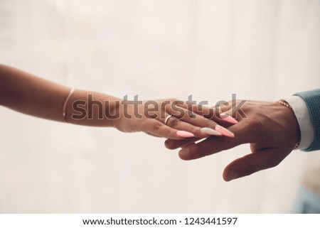 Newlyweds holding hands, their weddingbands showing.White background.