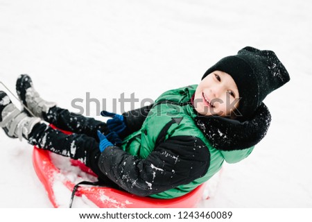 Little children on sledges, walking in the winter park. The boy play snow with parents. Close up. Portrait happy childrens.