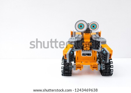 Orange plastic robot programmable on Scratch. STEM plus art is equal to STEAM. Science, technology, engineering, art, mathematics. The concept of new methods of teaching children and teenagers. Royalty-Free Stock Photo #1243469638