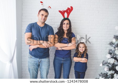 Christmas family photo. Father, mother and daughter are wearing christmas funny horns.