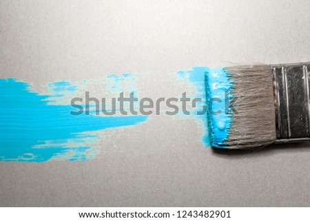 paint brush in blue paint on an unpainted flat surface, copyspace