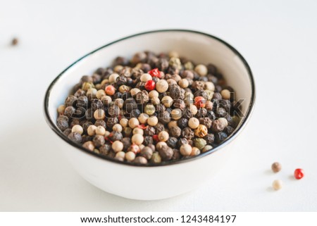 Various kinds of pepper seeds in a white bowl on a white background. Macro photography.