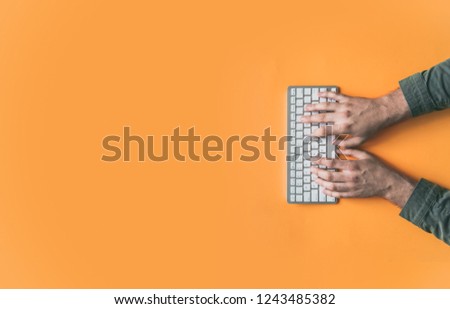 Top view of mans hans wiriting on a keyboard on colorful background, enough room for text