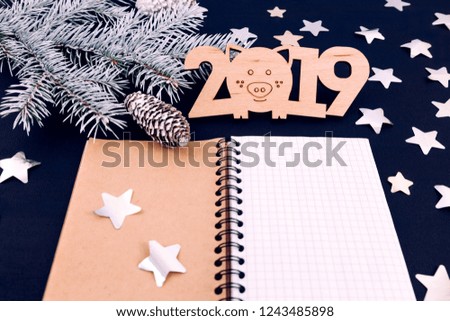White branch of a Christmas tree on a blue background with stars, top view. Figures 2019, notepad, concept plans for the New Year. Festive greeting card.