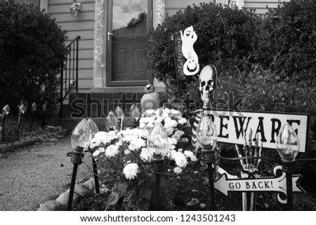 Monochrome Version of Pumpkins Halloween Enter if You Dare Signs with Skeleton Decorations Adorn the Flower Garden Leading to the Front Doorsteps of a Townhome in Burke, Virginia