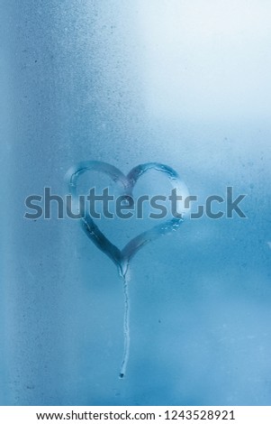 Heart on the glass and drops of water. Condensation on the window