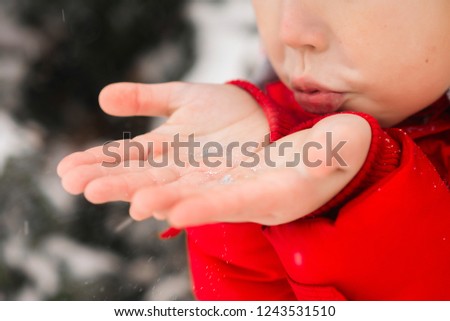 Winter fun. A child blows snow from the palms. Winter, street, snowflake.