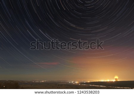 Star trails in the night sky. A view of the starry space in the background of the city illumination.